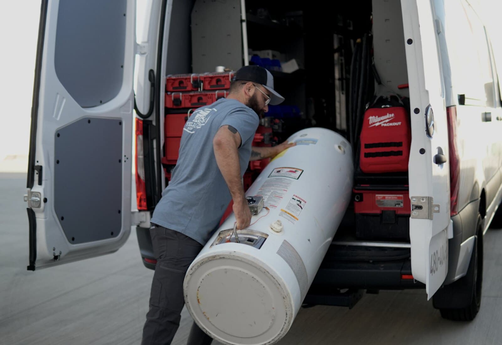 Yellowstone Plumbing technician loading a removed tank water heater into the company van