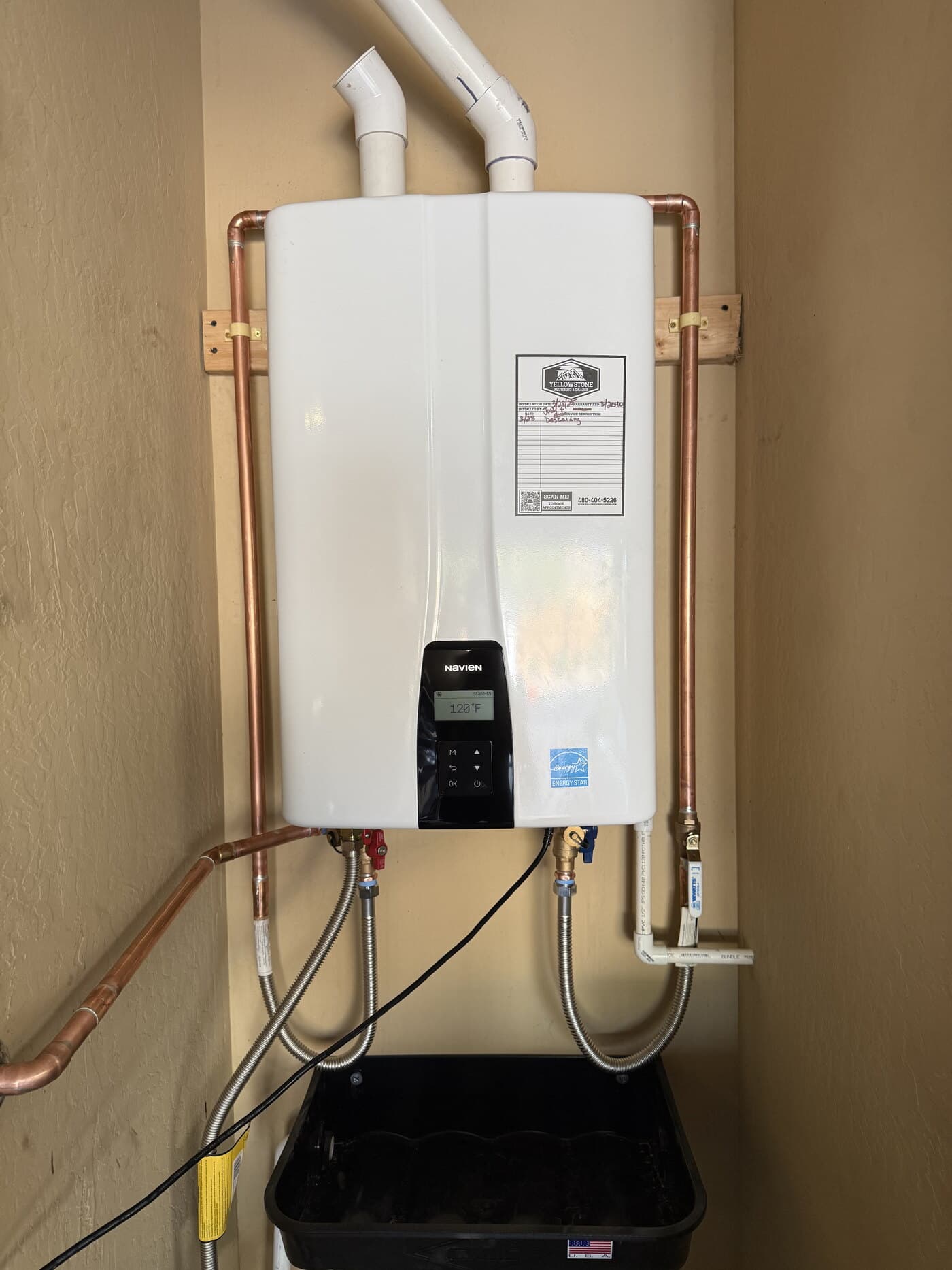 Navien tankless water heater installed and wall-mounted by Yellowstone Plumbing, with copper supply lines and the Yellowstone service tag